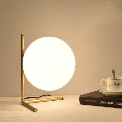 Creative glass desk lamp with three-tone LED lighting on a wooden desk.