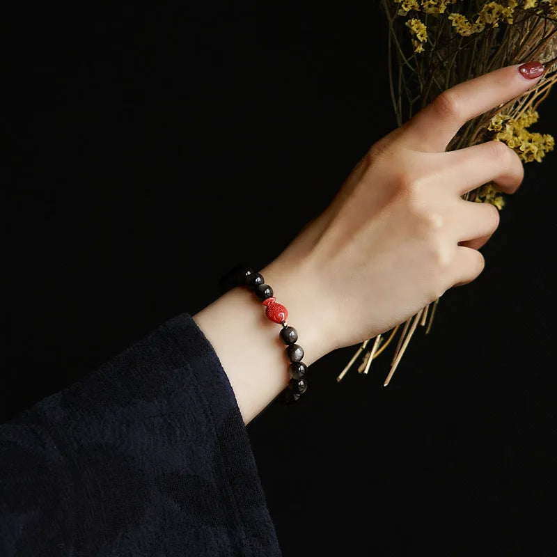 Natural obsidian round bead bracelet with red cinnabar fungus decorative elements.