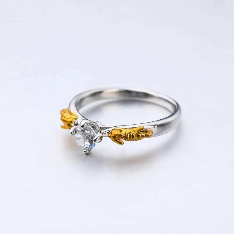 Copper crown design crystal ring in black gold finish on a size chart.