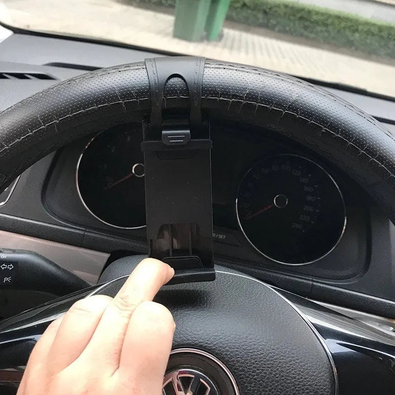 Black universal steering wheel phone holder clip mounted on a car steering wheel holding a smartphone.