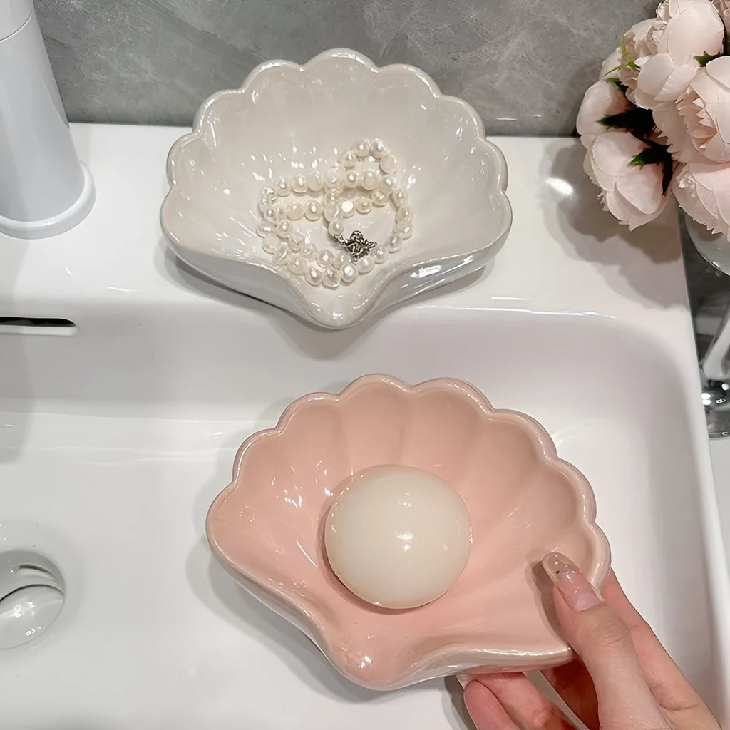 White or pink plastic shell-shaped soap dish for bathroom countertop or shower storage.