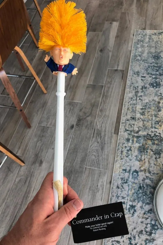 Yellow plastic Donald Trump novelty toilet brush with hanging slot.