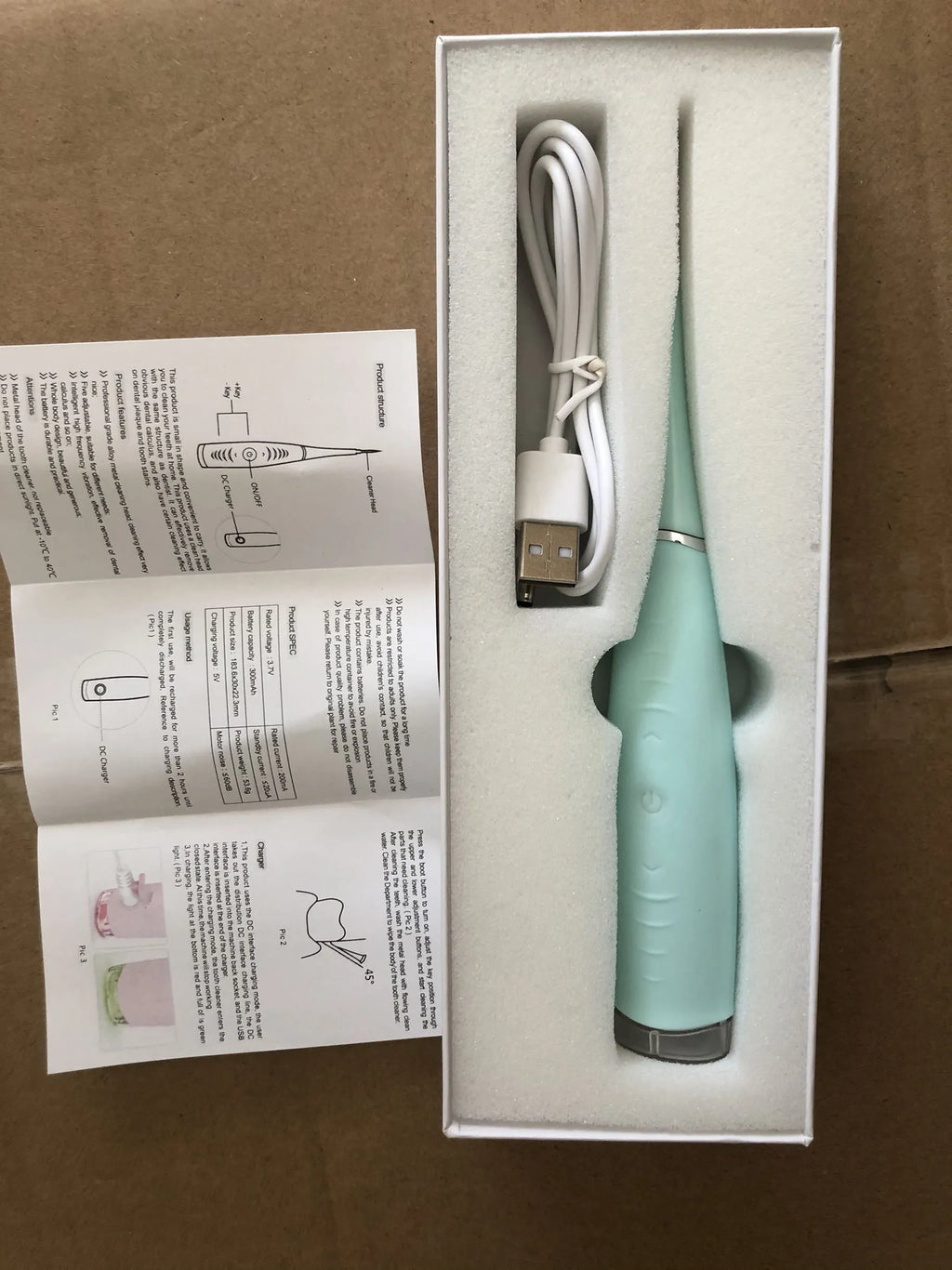Pink and blue waterproof electric tooth scaler with integrated handle on a bathroom counter.