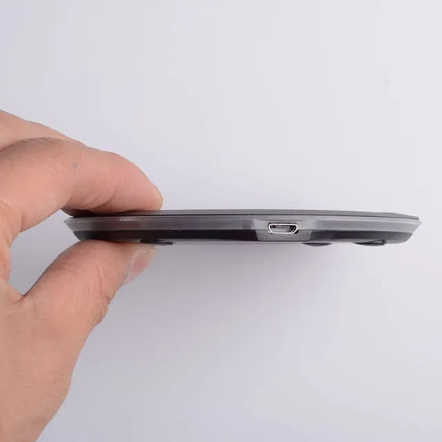 Ultra-thin wireless charger for mobile phone, black, with USB cable, showing charging indicator light