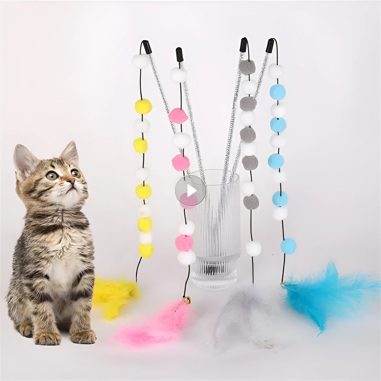 Grey, yellow, and blue acrylic pompon cat teaser stick with feather and bell, shown at 31cm length.