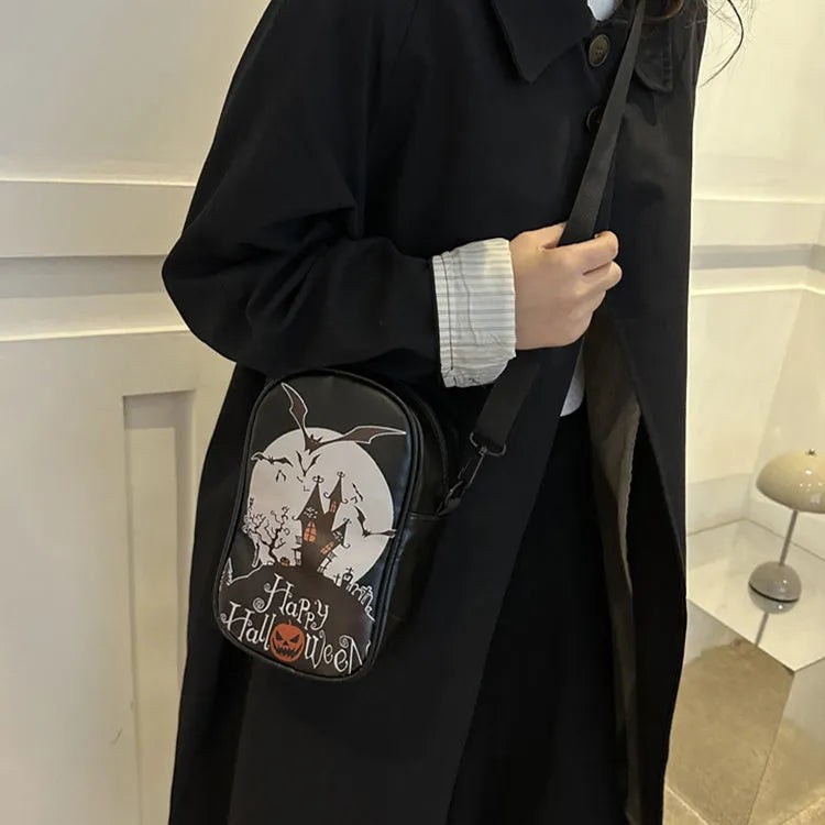 Black Halloween crossbody bag with graffiti print of cartoon pumpkins, ghosts, and bats.