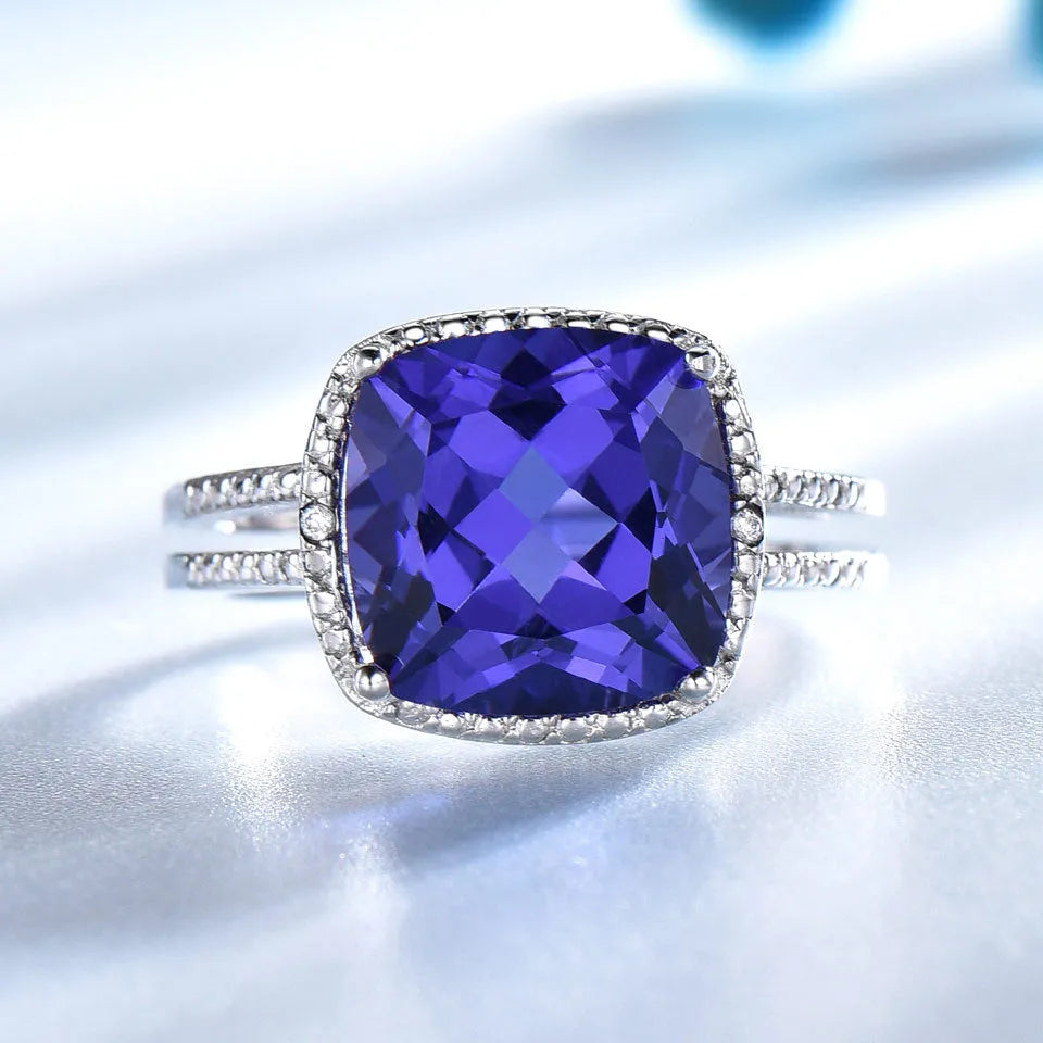 Blue tanzanite stone set in a sterling silver women's ring on a white background.