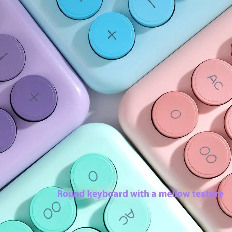 Gradient colour desktop calculator with large keys on a desk, shown in violet, pink, blue, and green colour options.