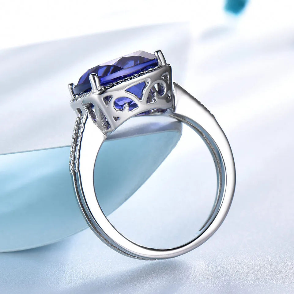 Blue tanzanite stone set in a sterling silver women's ring on a white background.