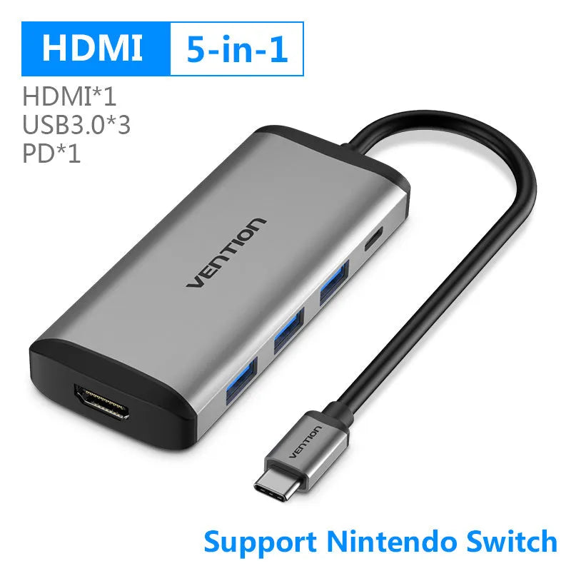 Deep grey USB-C to HDMI hub with Ethernet, USB ports, and memory card slots on a desk next to a laptop.