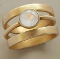 Gold-plated hollow geometric titanium steel ring with micro-inlaid white chalcedony stone detailing.