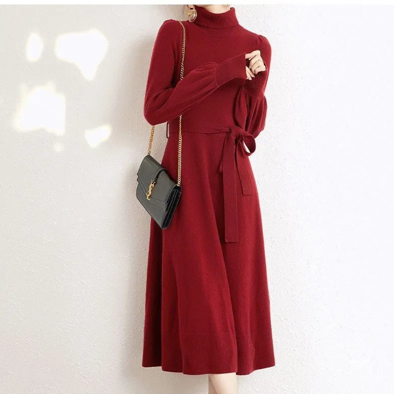 Adult woman wearing a rose red loose-knit turtleneck sweater dress with a flared midi skirt and elastic waist.