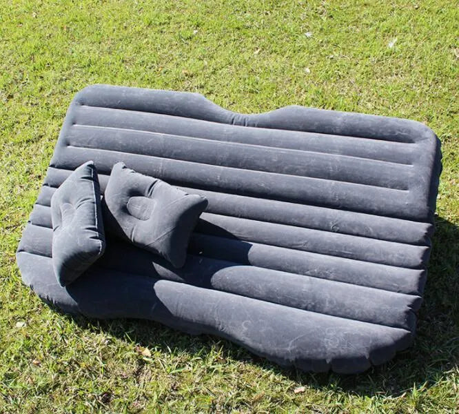 Black inflated car bed with flocked surface and two pillows inside a five-seater vehicle.