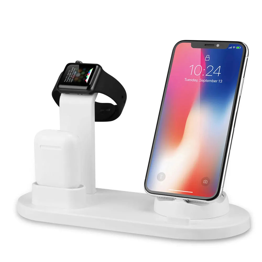 White three-in-one headphone charging stand dock on a desk with a USB cable.