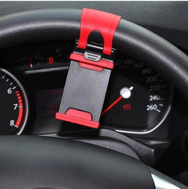 Black universal steering wheel phone holder clip mounted on a car steering wheel holding a smartphone.
