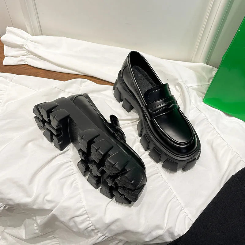 Women's wide fit patent leather loafers with a muffin heel and shallow opening on a rubber sole.