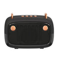 Compact portable black Bluetooth subwoofer speaker with USB port on a wooden table.