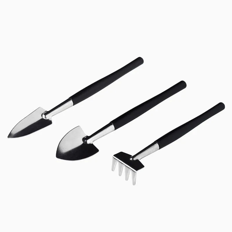 Black mini succulent garden tool set with 14 pieces including tweezers, shovel, spray bottle, and a square cushion laid out.