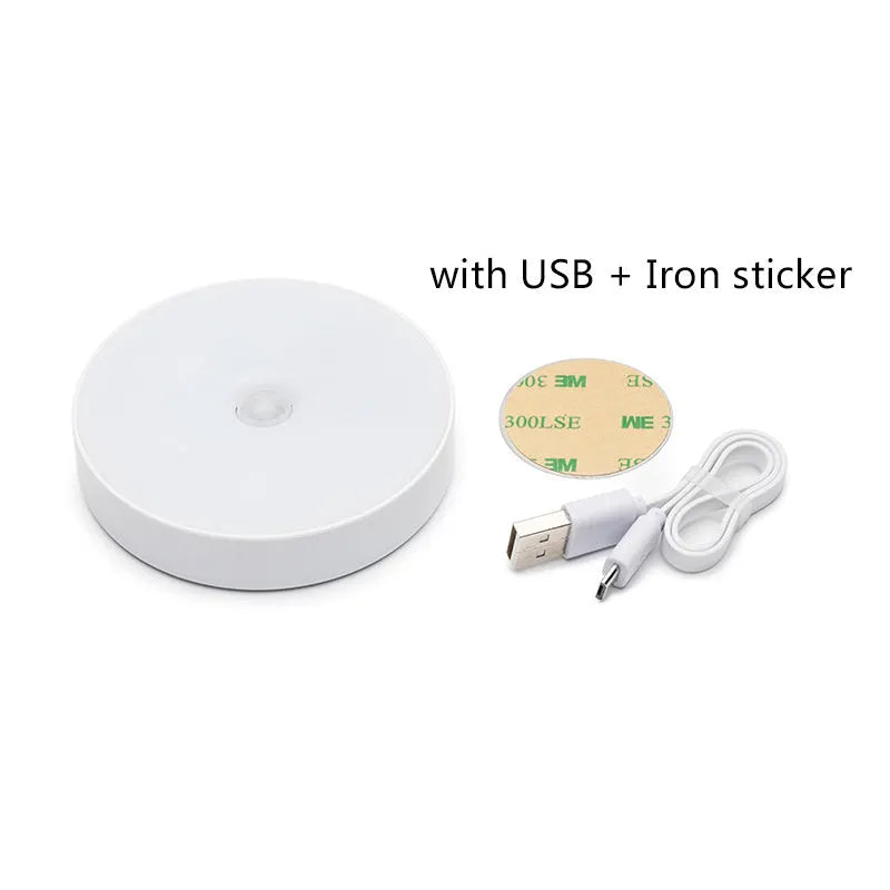 Small circular beige and white LED body sensor night light with USB charging cable on a surface.