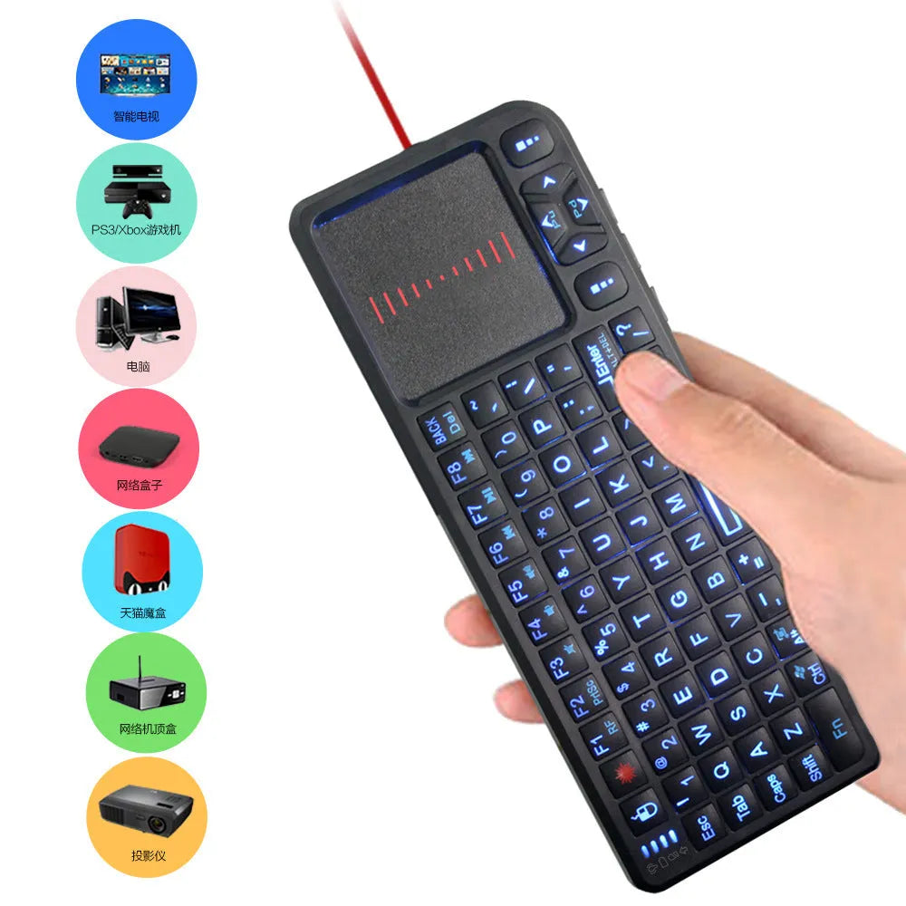 Black wireless mini keyboard with touch screen and laser pointer on a desk next to a laptop
