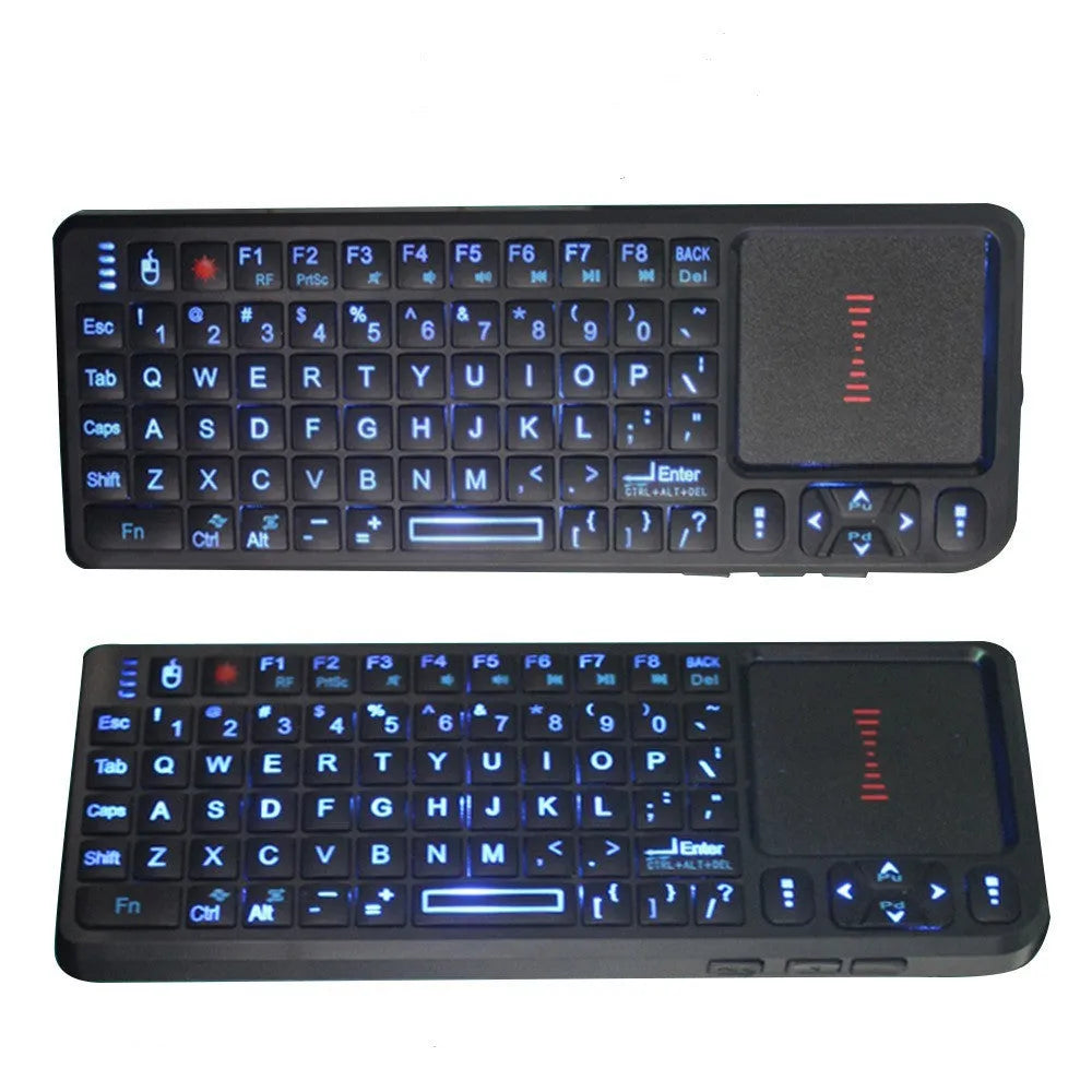 Black wireless mini keyboard with touch screen and laser pointer on a desk next to a laptop