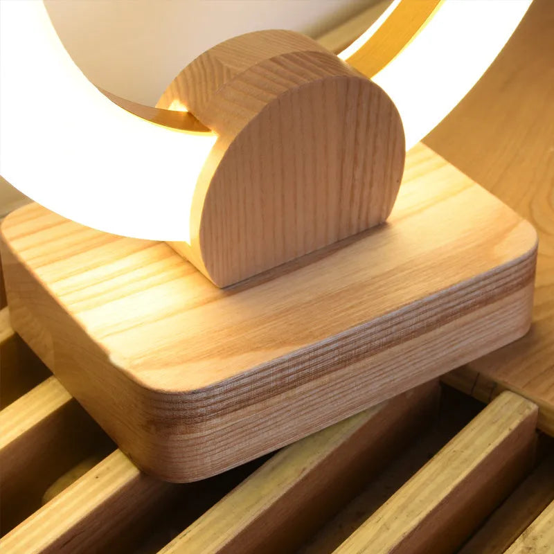 Nordic style circular wooden chandelier with a white acrylic shade hanging from a ceiling.