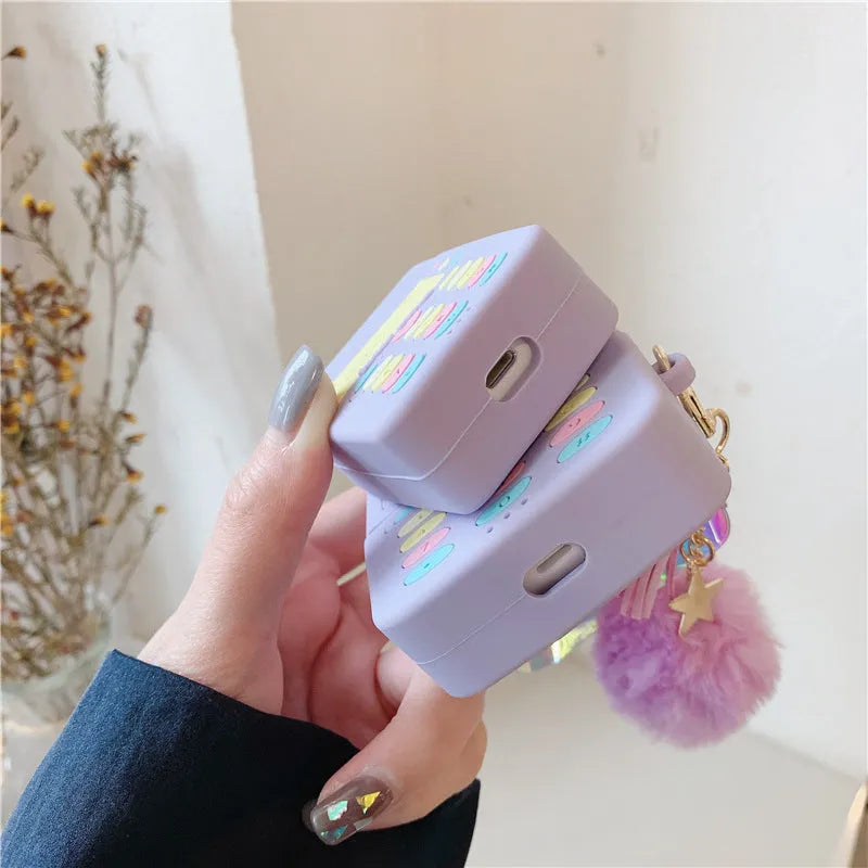 Purple silicone protective case for Apple AirPods with a white fur ball pendant attached.