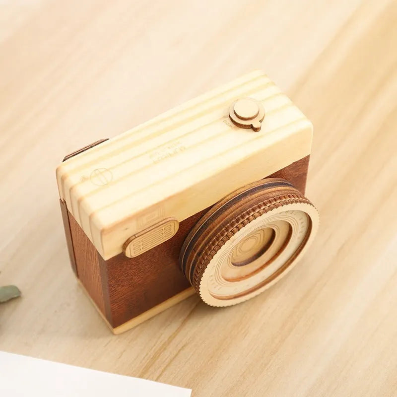 Camera-shaped wooden music box rotating on wooden surface with pine wood construction