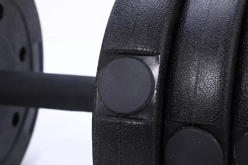 Pair of black rubber coated round head dumbbells 10kg each on a gym floor with indoor fitness equipment