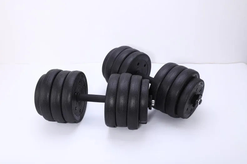 Pair of black rubber coated round head dumbbells 10kg each on a gym floor with indoor fitness equipment