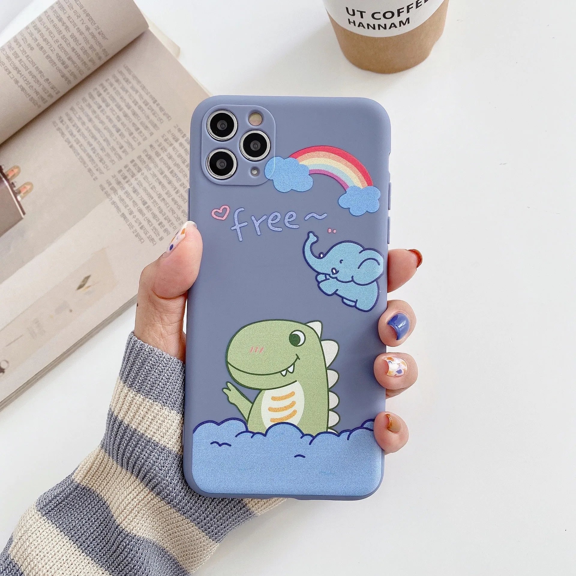 Blue frosted soft shell iPhone case with cartoon dinosaur print next to pink case with cat girl print.