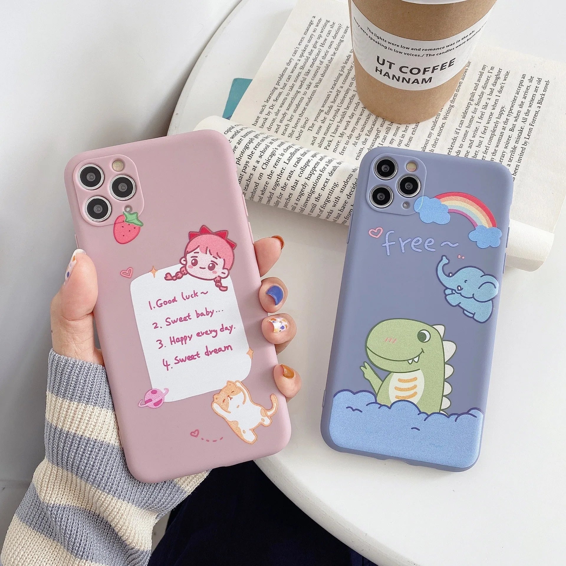 Blue frosted soft shell iPhone case with cartoon dinosaur print next to pink case with cat girl print.