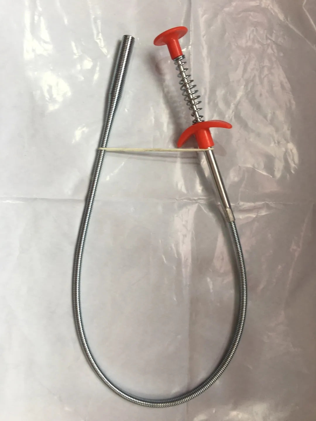 Black flexible sewer dredger spring drain cleaning tool with a textured grip on a white background.
