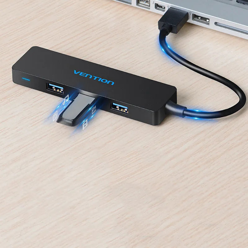 Black four-port USB 3.0 hub with a short 15cm cable on a desk.