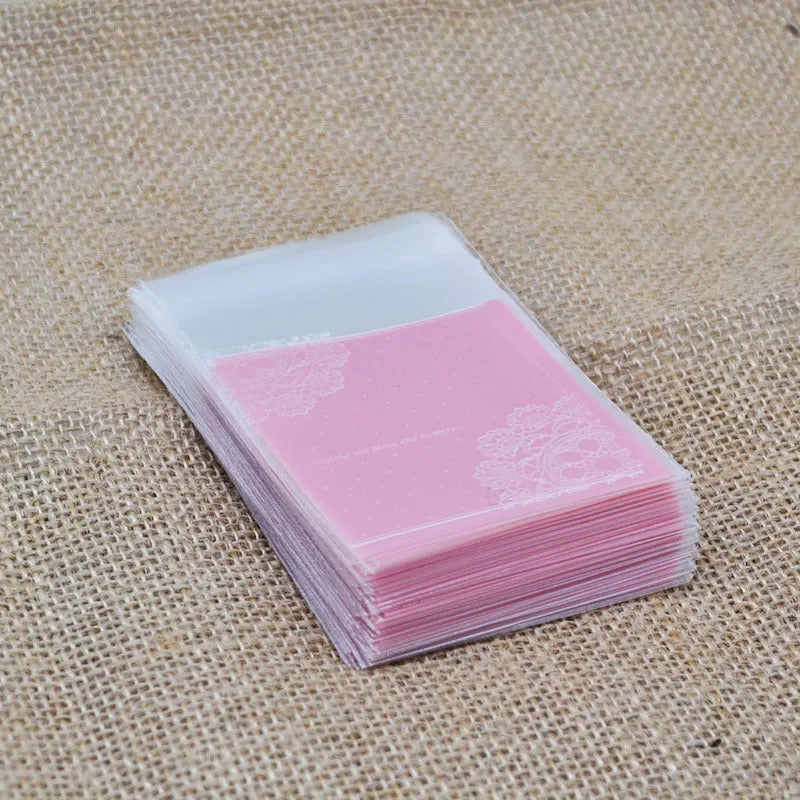 Pink self-adhesive plastic packaging bags with UV printing, shown in a pack of 100.