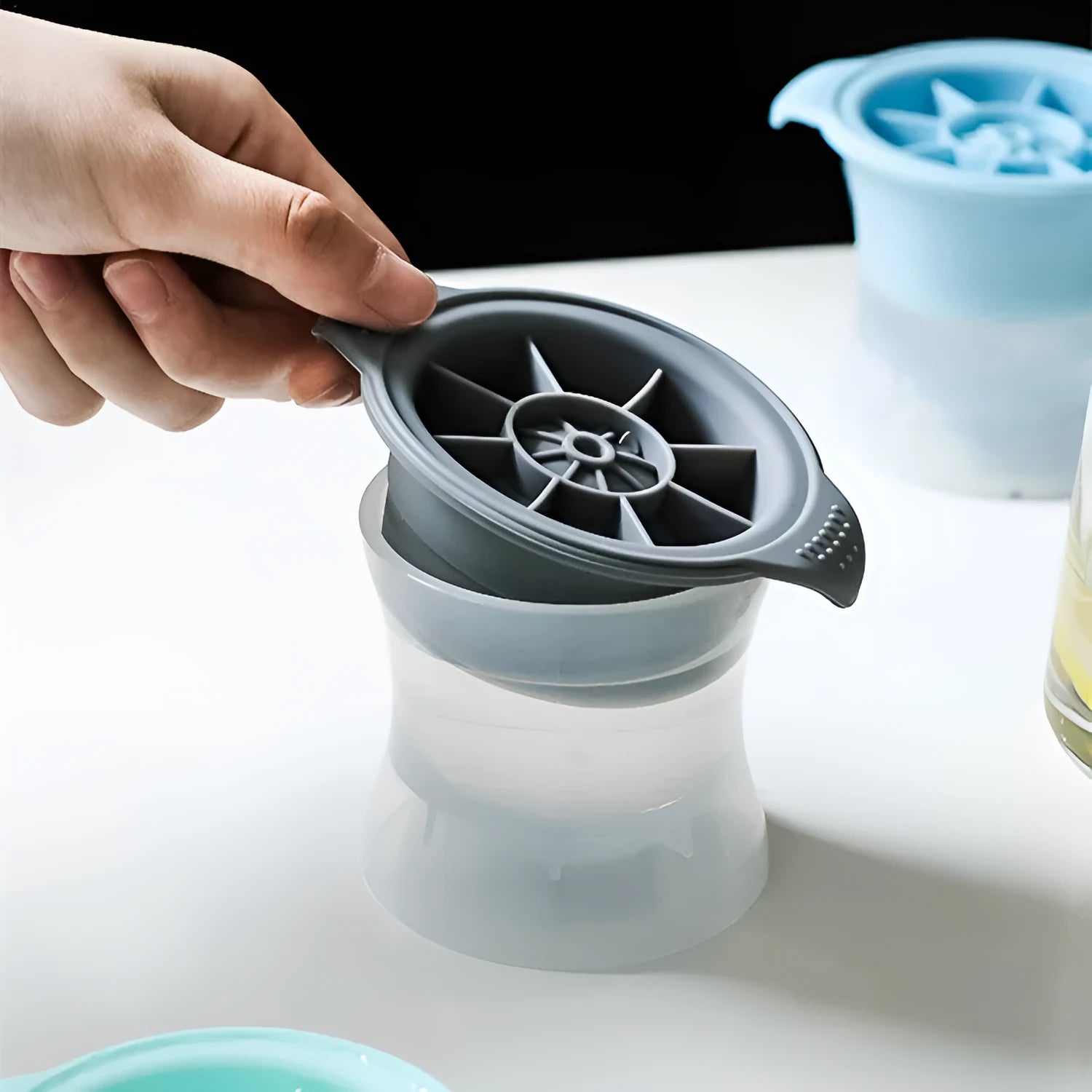Flexible silicone ice tray making large hockey puck and round geometric ice cubes in assorted colours.