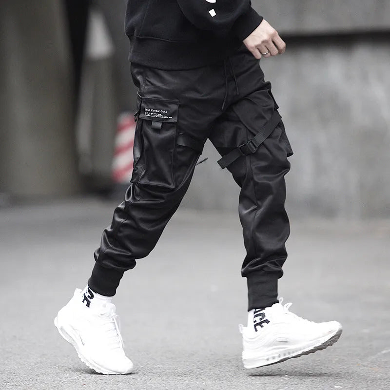 Black cotton cargo pants with tether closure, loose fit, ankle length, on a model