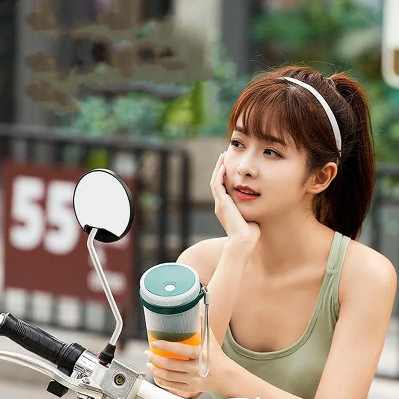 Pink and green portable electric juicer cup with USB charging port and round feeding lid.