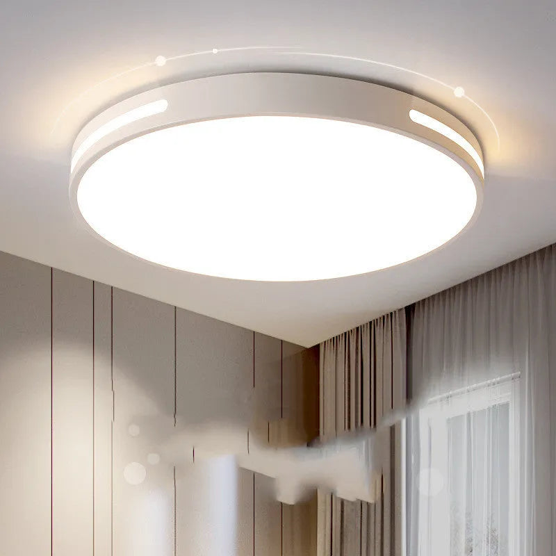 Round modern acrylic LED ceiling lamp with remote control on a white bedroom ceiling.