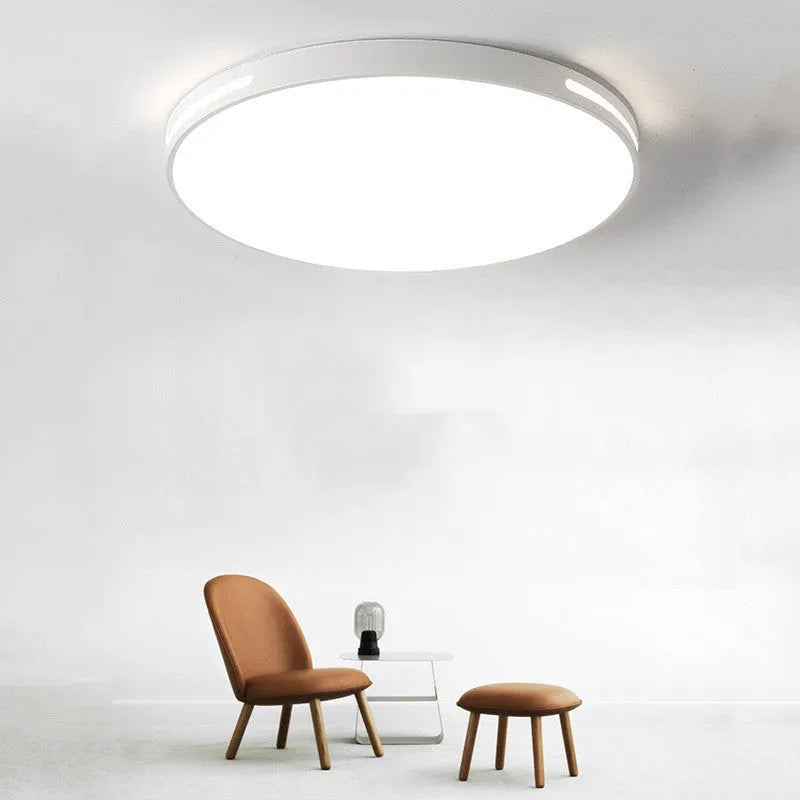 Round modern acrylic LED ceiling lamp with remote control on a white bedroom ceiling.