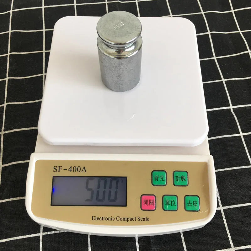 Silver electronic kitchen scale with LCD display showing weight, placed on a kitchen counter.