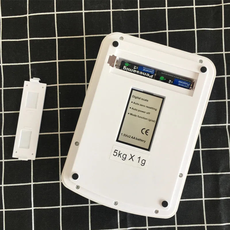 Silver electronic kitchen scale with LCD display showing weight, placed on a kitchen counter.