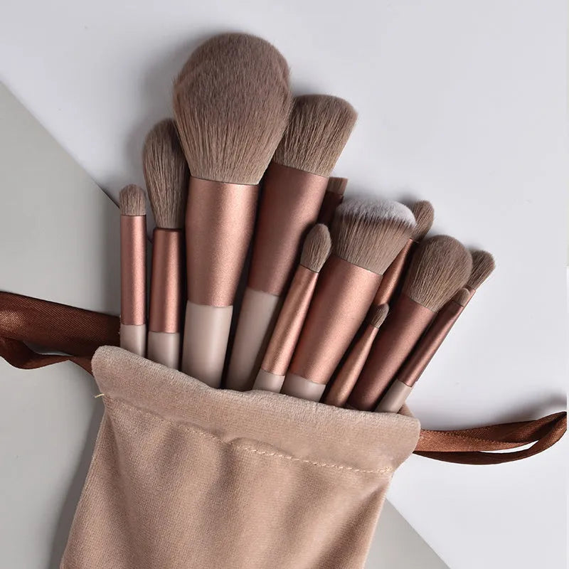 Thirteen Morandi green makeup brushes laid out, including blush and powder brushes