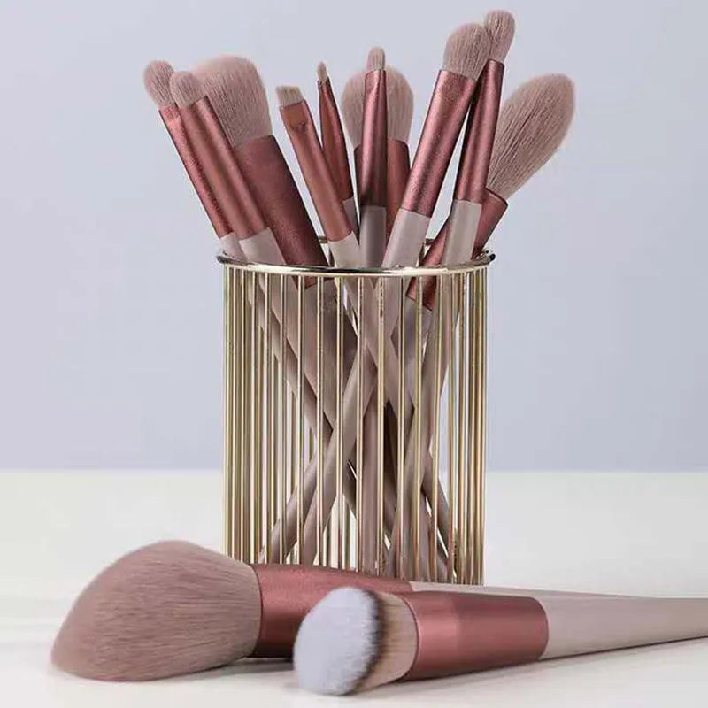 Thirteen Morandi green makeup brushes laid out, including blush and powder brushes