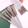 Thirteen Morandi green makeup brushes laid out, including blush and powder brushes