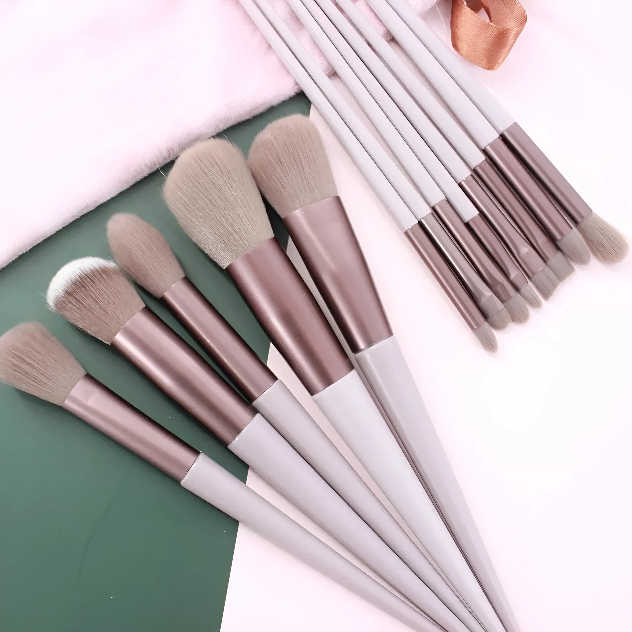 Thirteen Morandi green makeup brushes laid out, including blush and powder brushes