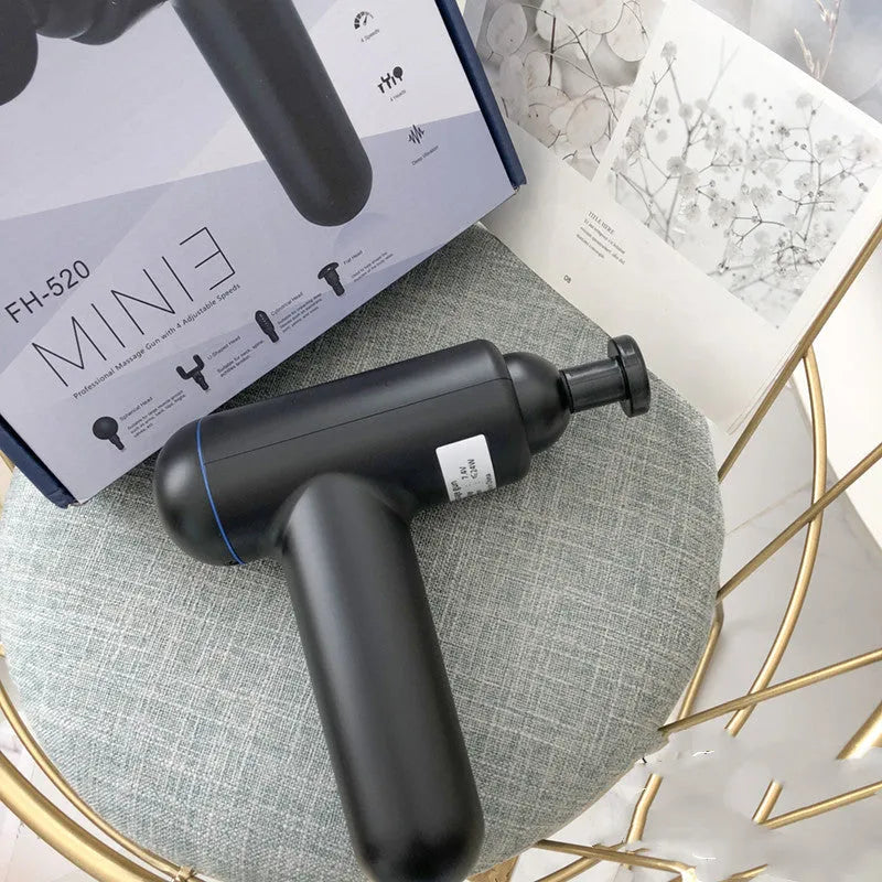 Black fascia gun muscle massager with a round percussion head on a grey background.