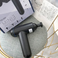 Black fascia gun muscle massager with a round percussion head on a grey background.
