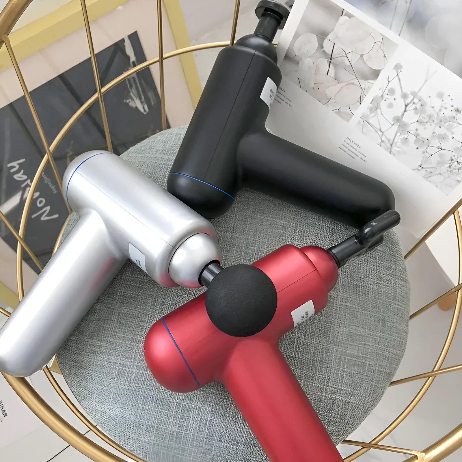 Black fascia gun muscle massager with a round percussion head on a grey background.