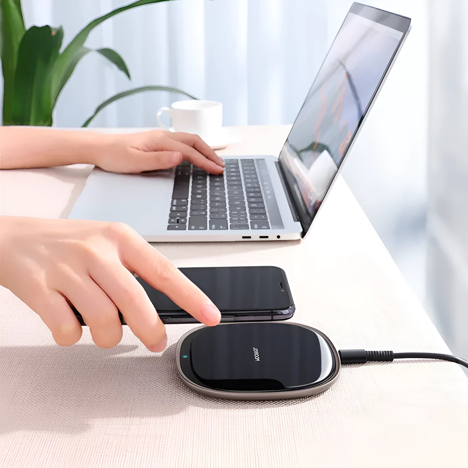 Square black 15W wireless phone charger with a glass top and zinc alloy frame on a desk.